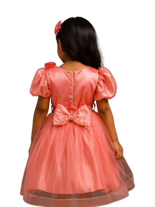 Pink dress with a large bow on the back of a child against a white background