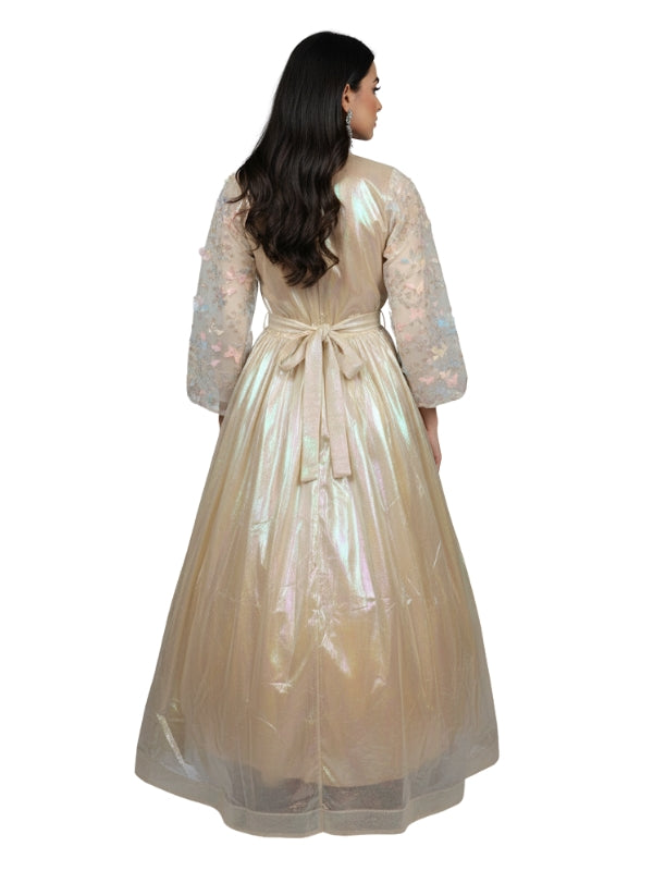 Woman wearing a beige long dress with a sheer overlay on a white background