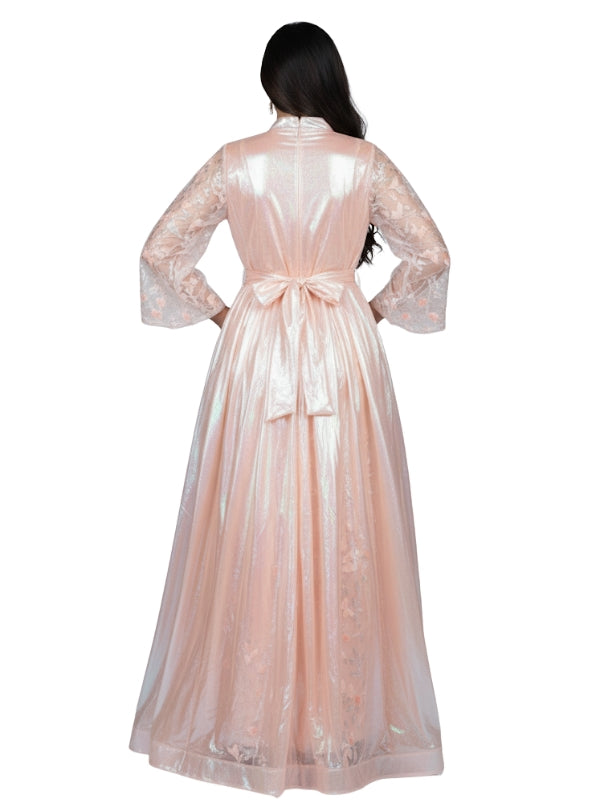 Woman wearing a long, light pink lace dress with a bow on a white background