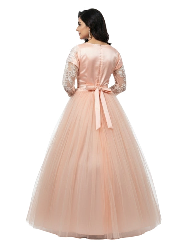 Woman wearing a peach-colored gown with lace sleeves on a white background